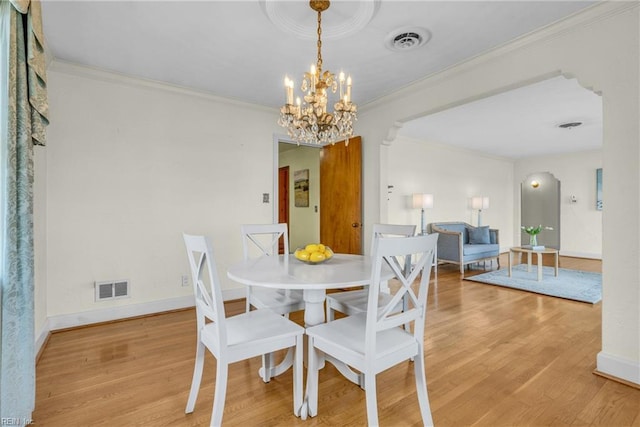 dining area with an inviting chandelier, crown molding, and hardwood / wood-style flooring