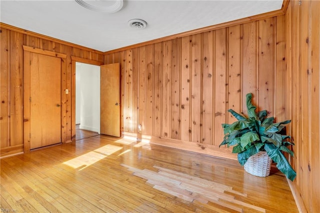 unfurnished room featuring hardwood / wood-style flooring, wood walls, and crown molding