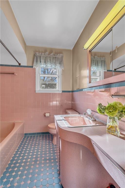 full bathroom with toilet, tub / shower combination, tile patterned floors, vanity, and tile walls