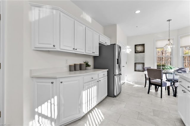 kitchen featuring stainless steel fridge, white cabinets, and pendant lighting