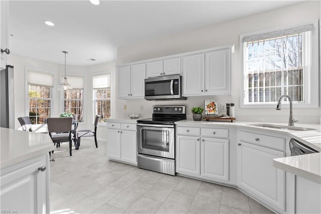 kitchen featuring pendant lighting, white cabinetry, sink, and stainless steel appliances