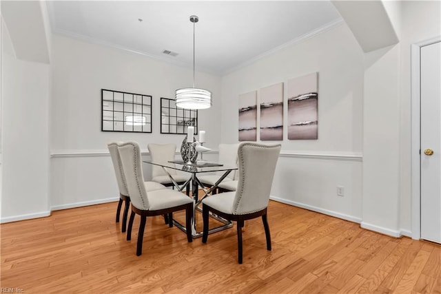 dining space with light wood-type flooring and ornamental molding