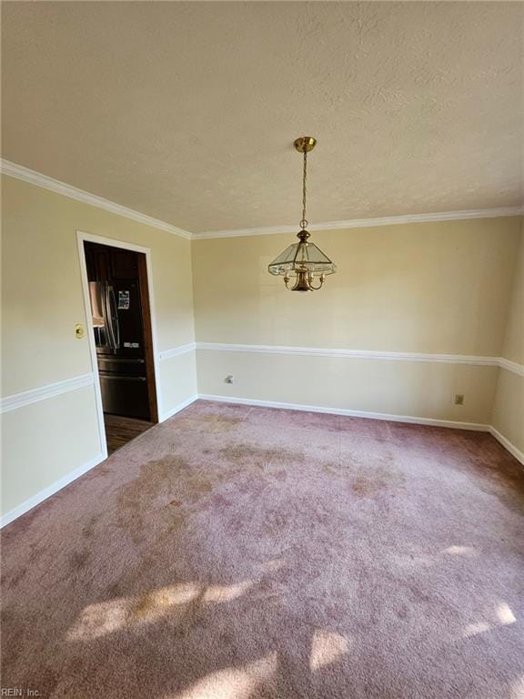 carpeted spare room featuring ornamental molding, a textured ceiling, and a notable chandelier