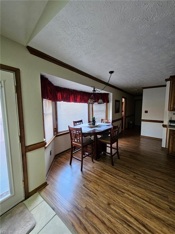 dining space with plenty of natural light, wood-type flooring, and a textured ceiling