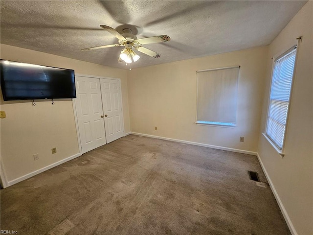 unfurnished bedroom with carpet flooring, ceiling fan, and a textured ceiling