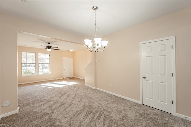 carpeted spare room featuring ceiling fan with notable chandelier