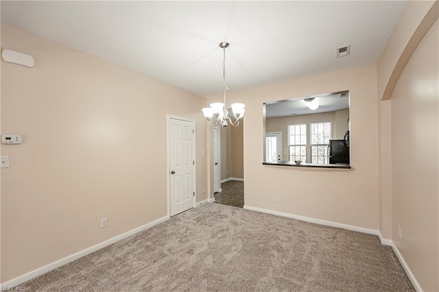 spare room featuring carpet floors and an inviting chandelier