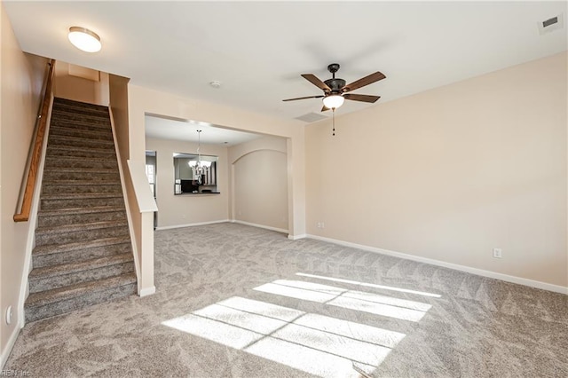 unfurnished living room featuring carpet floors and ceiling fan with notable chandelier