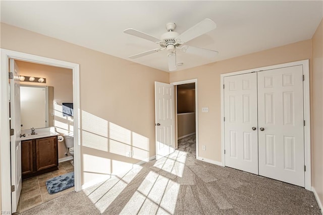 bedroom with ensuite bathroom, light colored carpet, ceiling fan, sink, and a closet