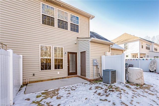 snow covered rear of property with central AC unit