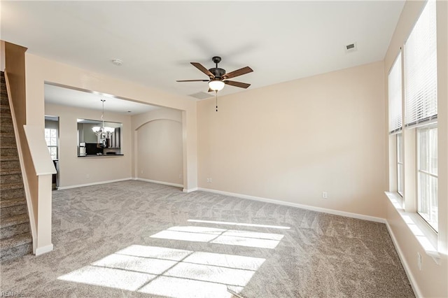 unfurnished room with ceiling fan with notable chandelier and light colored carpet