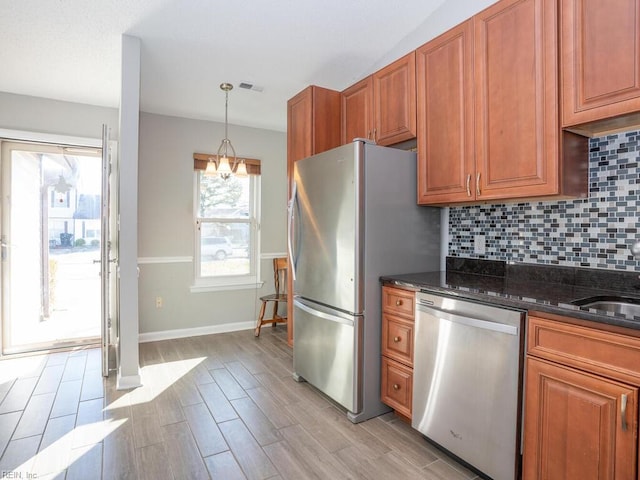 kitchen featuring hanging light fixtures, an inviting chandelier, dark stone counters, decorative backsplash, and appliances with stainless steel finishes