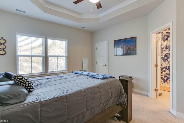 carpeted bedroom featuring ensuite bathroom, a raised ceiling, and ceiling fan