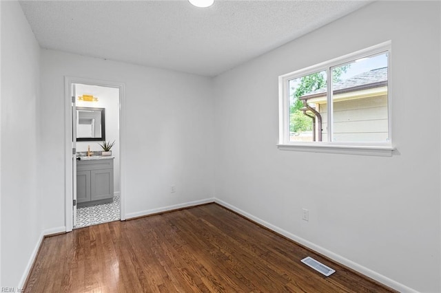 empty room featuring a textured ceiling and dark wood-type flooring