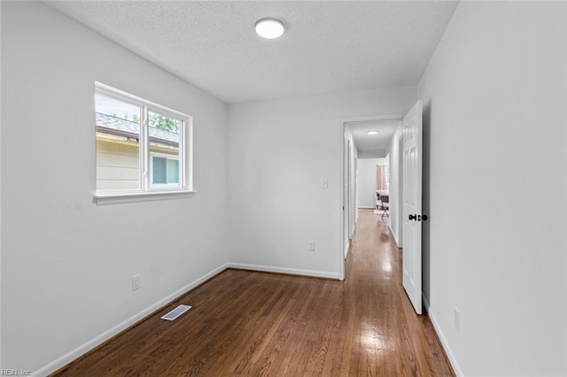 empty room featuring wood-type flooring and a textured ceiling