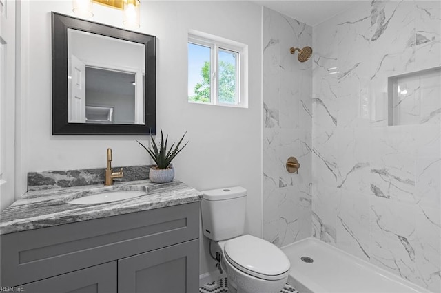 bathroom featuring a tile shower, vanity, and toilet