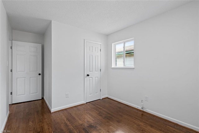 unfurnished bedroom with dark hardwood / wood-style flooring, a textured ceiling, and a closet