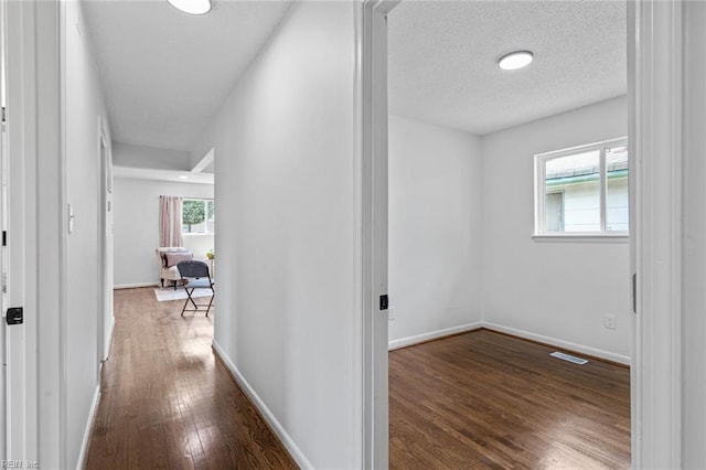 corridor with dark hardwood / wood-style flooring and a textured ceiling