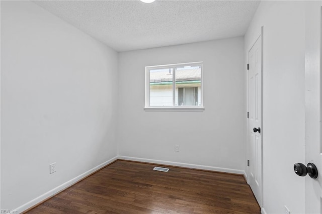 spare room with dark wood-type flooring and a textured ceiling