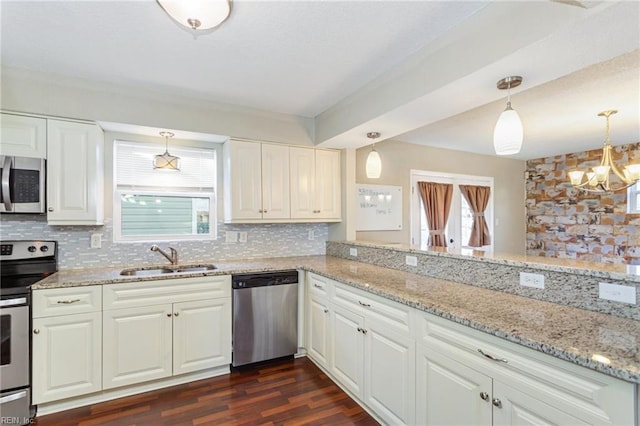 kitchen with tasteful backsplash, decorative light fixtures, sink, white cabinetry, and appliances with stainless steel finishes