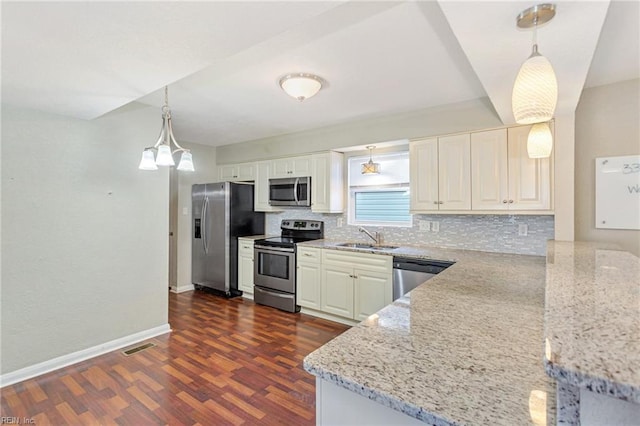 kitchen with light stone countertops, sink, stainless steel appliances, and pendant lighting