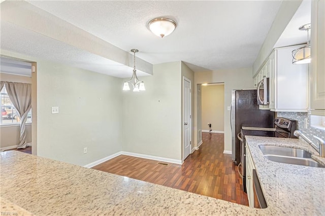 kitchen featuring pendant lighting, white cabinets, appliances with stainless steel finishes, dark hardwood / wood-style flooring, and a chandelier