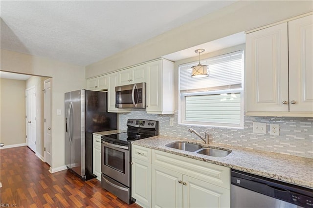 kitchen featuring light stone countertops, pendant lighting, appliances with stainless steel finishes, sink, and backsplash