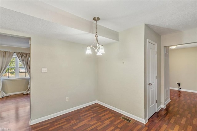 unfurnished dining area with dark hardwood / wood-style floors, an inviting chandelier, and a textured ceiling