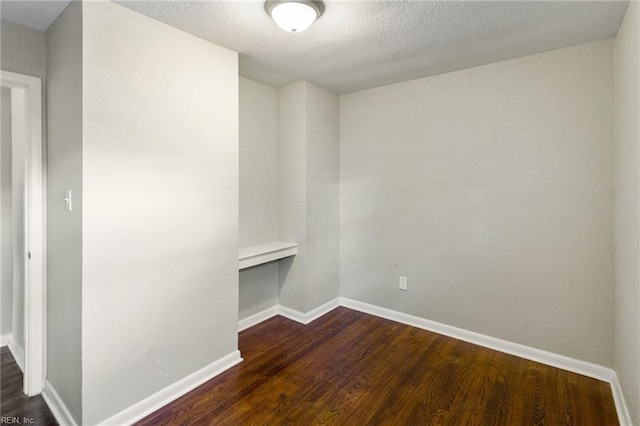 unfurnished room with a textured ceiling and dark hardwood / wood-style flooring