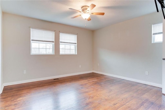 spare room featuring ceiling fan, a healthy amount of sunlight, and dark hardwood / wood-style floors