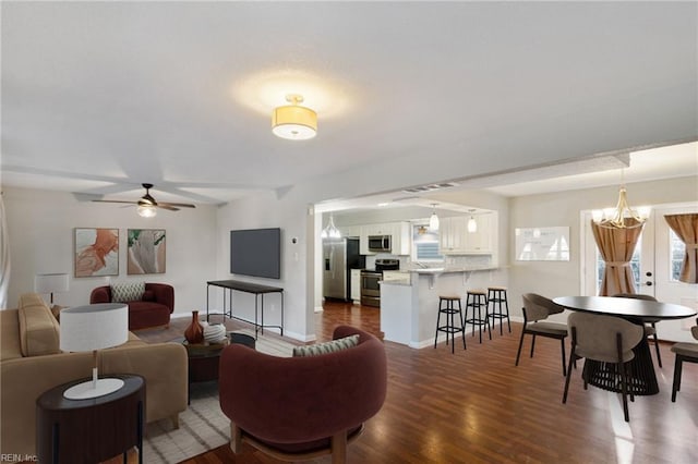 living room featuring dark hardwood / wood-style flooring and ceiling fan with notable chandelier