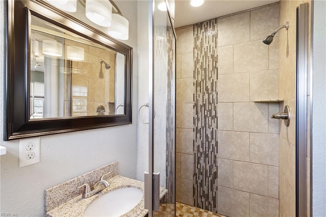 bathroom featuring a shower with shower door and vanity