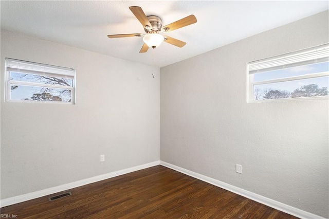 empty room with ceiling fan, dark hardwood / wood-style flooring, and a healthy amount of sunlight