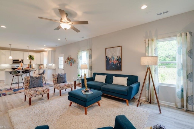 living room with ceiling fan and light wood-type flooring