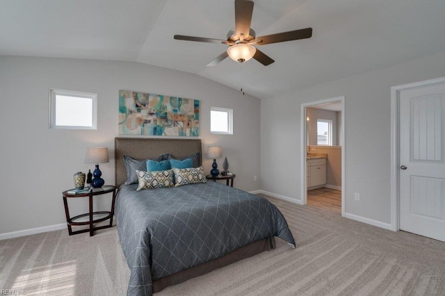 bedroom with ceiling fan, connected bathroom, vaulted ceiling, and light carpet