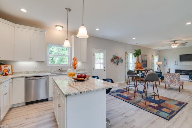 kitchen with light wood-type flooring, ceiling fan, white cabinetry, decorative light fixtures, and stainless steel dishwasher