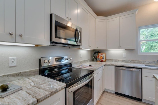 kitchen featuring sink, white cabinetry, light stone counters, and appliances with stainless steel finishes