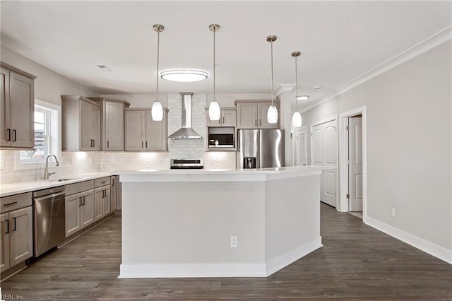 kitchen with wall chimney exhaust hood, hanging light fixtures, stainless steel appliances, a kitchen island, and sink