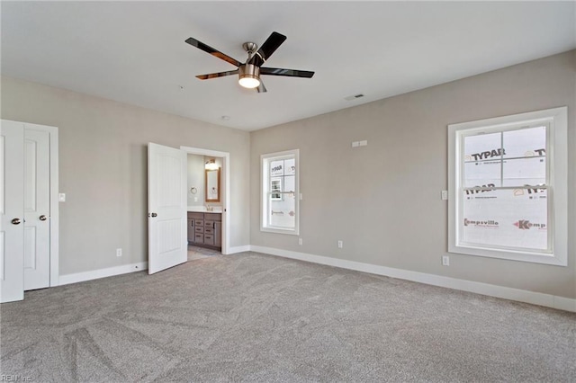 unfurnished bedroom featuring ceiling fan, ensuite bathroom, and carpet floors