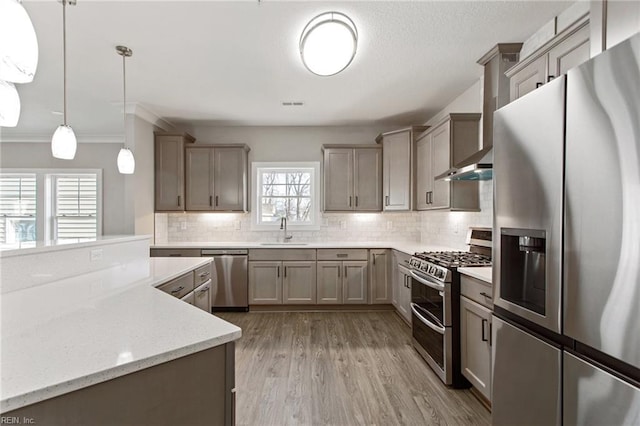 kitchen with light stone counters, hanging light fixtures, decorative backsplash, appliances with stainless steel finishes, and sink