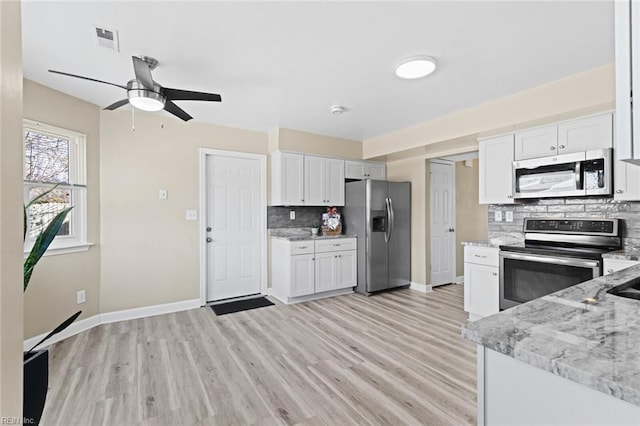 kitchen with light stone countertops, white cabinetry, appliances with stainless steel finishes, and tasteful backsplash