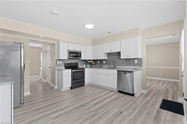 kitchen featuring white cabinetry, stainless steel appliances, light hardwood / wood-style flooring, light stone counters, and sink