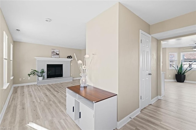 living room featuring ceiling fan, light hardwood / wood-style floors, and a fireplace