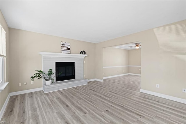 unfurnished living room featuring ceiling fan, a fireplace, and light hardwood / wood-style flooring