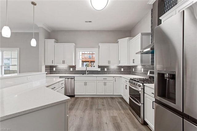 kitchen featuring stainless steel appliances, white cabinetry, sink, and pendant lighting