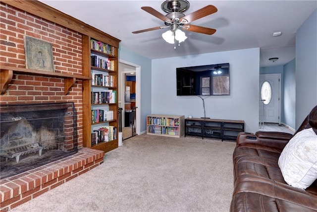 carpeted living room featuring a brick fireplace and ceiling fan