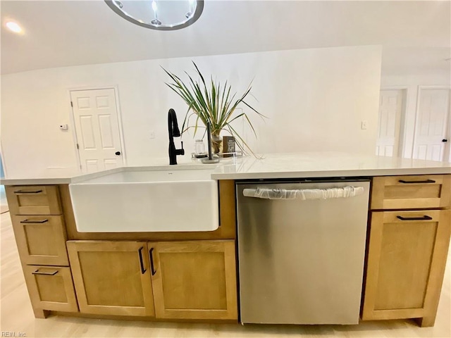 kitchen with stainless steel dishwasher, light countertops, an island with sink, and a sink