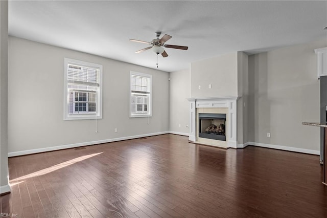 unfurnished living room with a fireplace, ceiling fan, and dark wood-type flooring