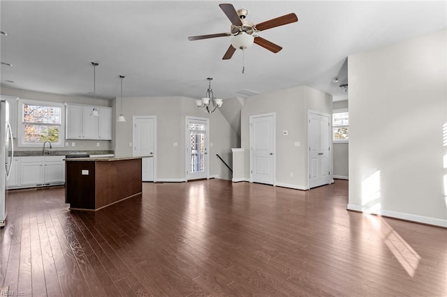 kitchen featuring a center island, light stone counters, white cabinets, decorative light fixtures, and ceiling fan with notable chandelier