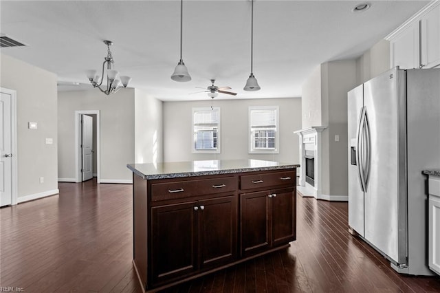 kitchen with ceiling fan with notable chandelier, hanging light fixtures, dark brown cabinetry, stainless steel refrigerator with ice dispenser, and dark hardwood / wood-style flooring